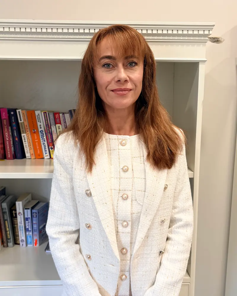 Светлана Кривенко в светлом жакете у книжного шкафа